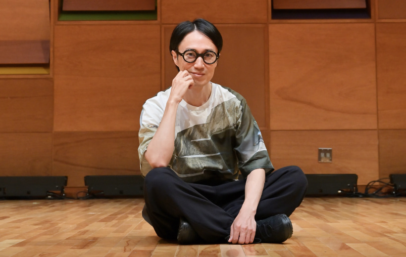 フロアに座り、微笑む今井教授