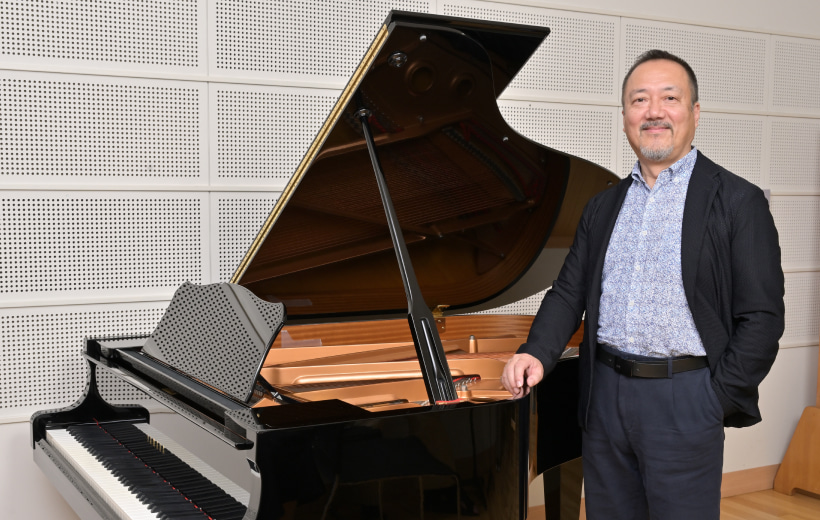 グランドピアノの傍に立つ黒田教授